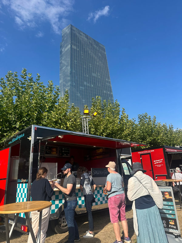Roter Foodtruck mit Gästen vor dem EZB-Turm in Frankfurt